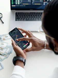 An individual assessing the amount of risk using charts and graphs on a computer and phone