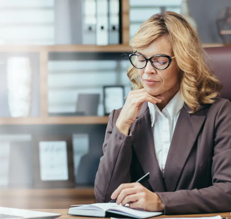 Senior business woman in an office looking at notebook.